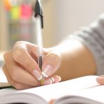 Woman hand writing in an agenda at home