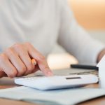 close up young man hand press on calculator to check and summary expense of home loan mortgage for refinance plan , people lifestyle concept