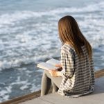 back-view-woman-reading-sea