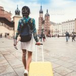 Rear view of woman with suitcase and umbrella relocate to live in Krakow